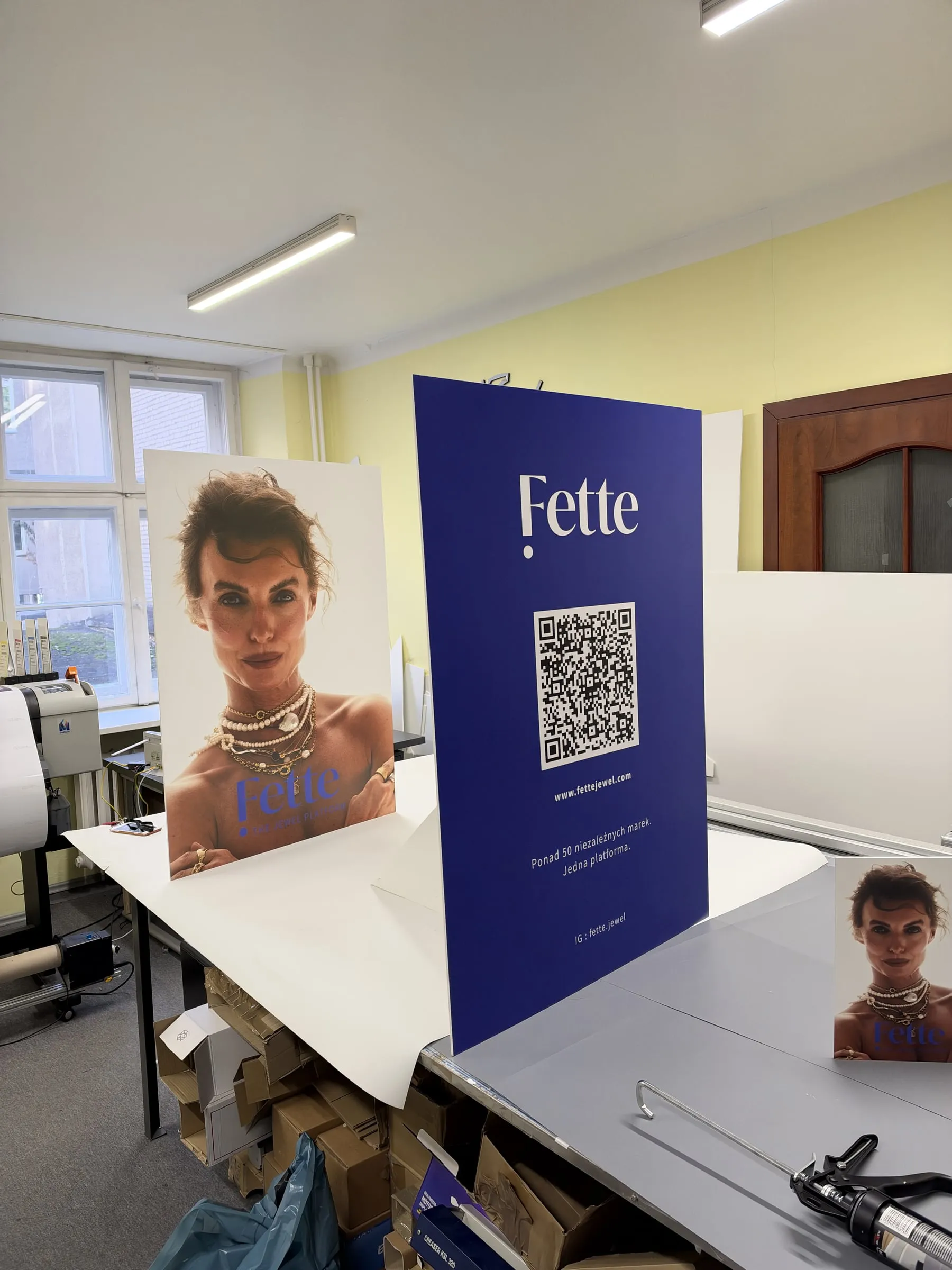 Dwa roll-upy z grafiką i kodem QR rozstawione w pracowni